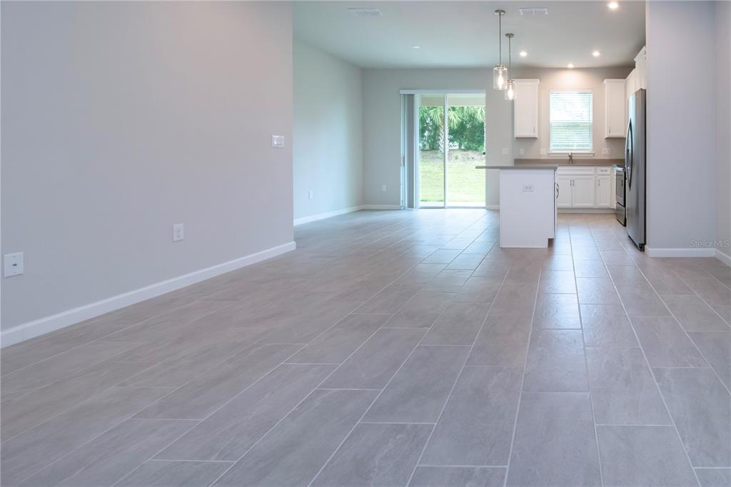 An open-concept kitchen and living area features light gray tile flooring and white cabinetry — 11518 ROLLING GREEN DRIVE, BRADENTON, FL