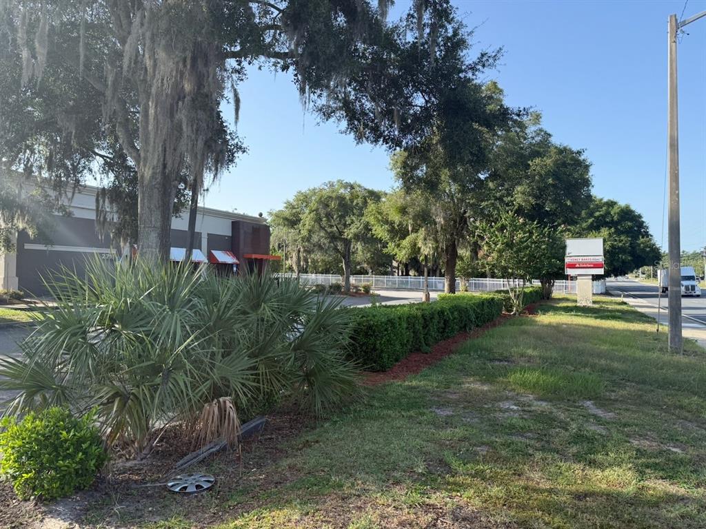 A commercial building with a parking lot, landscaping, and a roadside sign under a blue sky — 2709 SW 27TH AVENUE UNIT 103, OCALA, FL