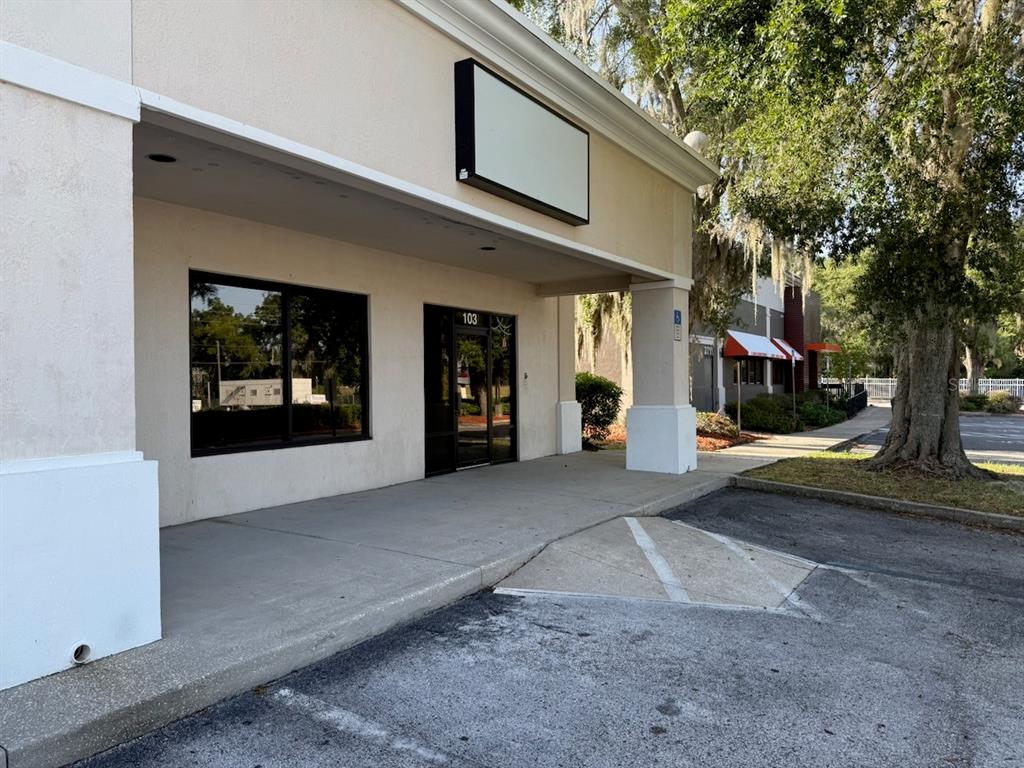 The exterior of a commercial building features a covered walkway, a glass entrance, and signage — 2709 SW 27TH AVENUE UNIT 103, OCALA, FL