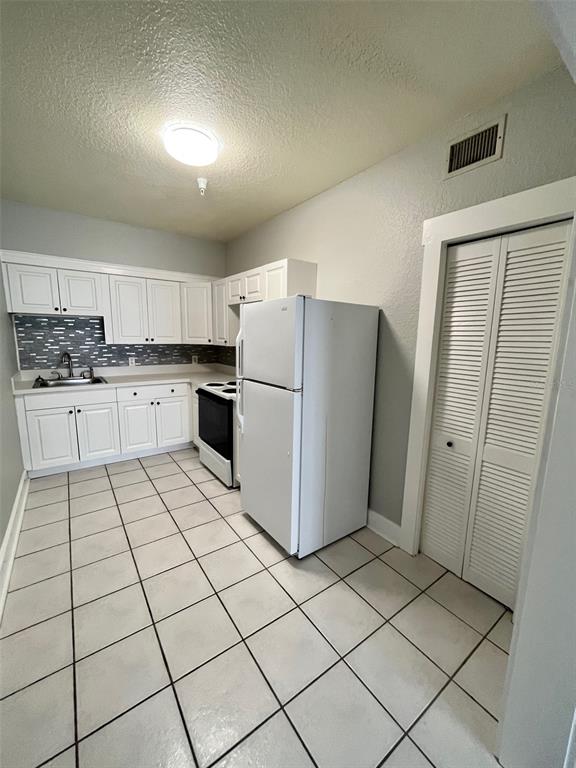 A kitchen features white cabinets, a white refrigerator, a stove, and light-colored tiled flooring — 644 4TH AVENUE S, ST PETERSBURG, FL