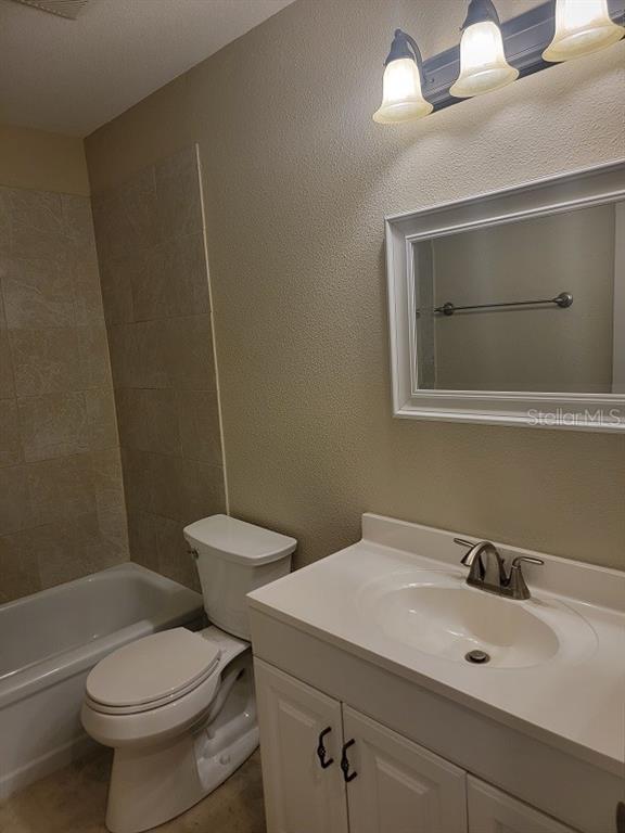 A bathroom features a white vanity, a toilet, and a bathtub with tiled walls — 474 HINTON STREET, PORT CHARLOTTE, FL