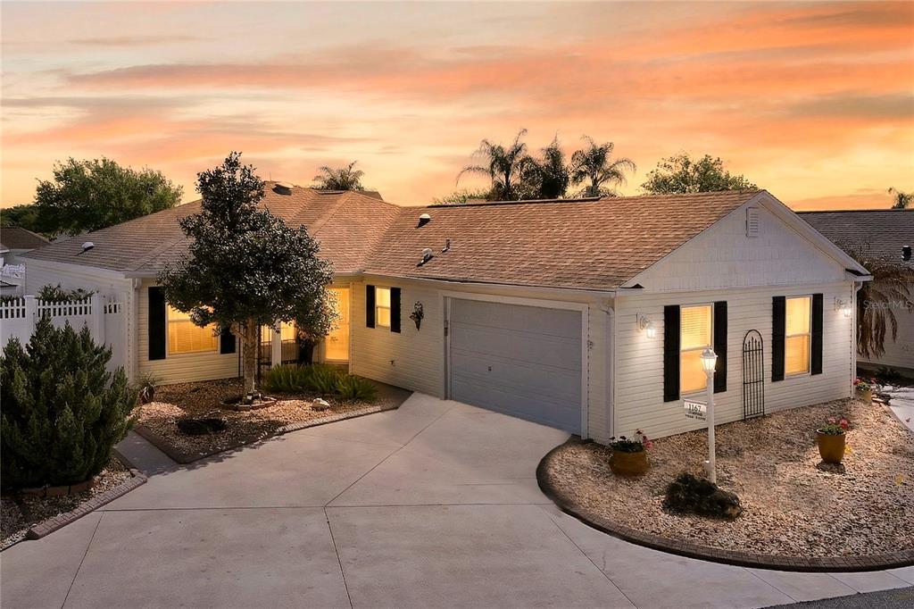 A single-story house with light siding, a two-car garage, and a gravel front yard — 1147 ELIZABETH COURT, THE VILLAGES, FL