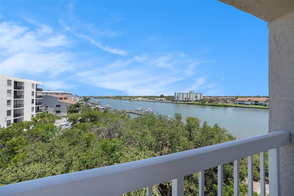 A view of a waterway and surrounding buildings from a balcony with a white railing — 19925 GULF BOULEVARD UNIT 407, INDIAN SHORES, FL