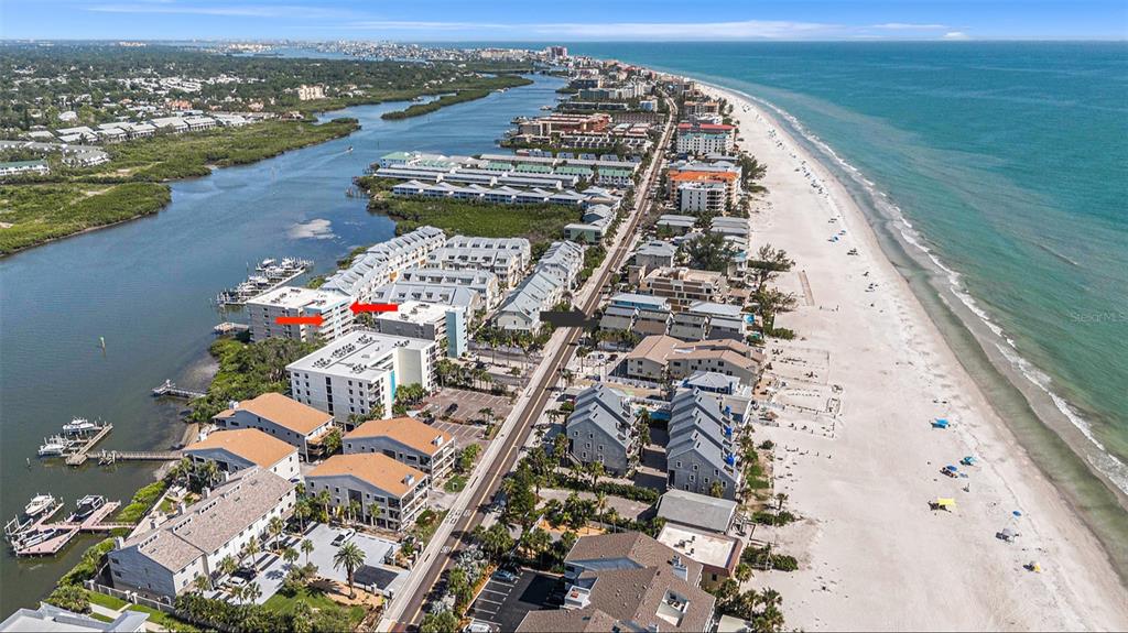 An aerial view of a coastal town featuring multi-story buildings, a road, and a sandy beach — 19925 GULF BOULEVARD UNIT 407, INDIAN SHORES, FL