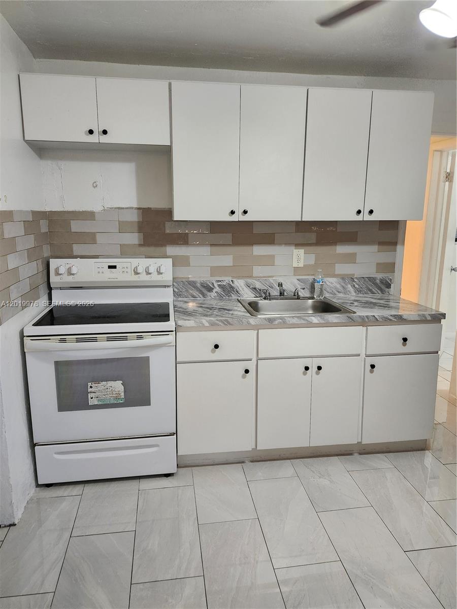 A small kitchen features white cabinets, a white electric stove, and a marble-patterned countertop — 551 NE 139th St # 551, North Miami FL 33161, NORTH MIAMI, FL
