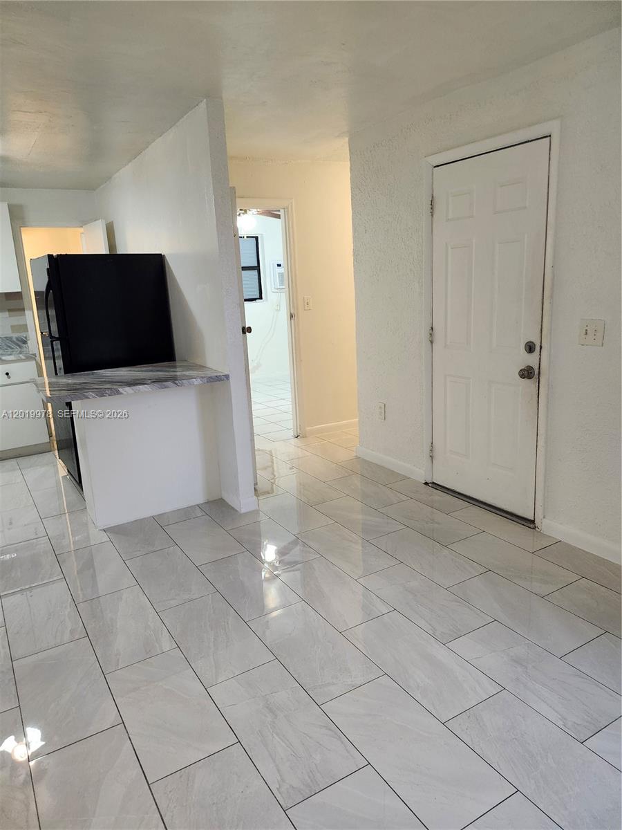 A kitchen area features a black refrigerator, marble-patterned counter, and light-colored tile flooring — 551 NE 139th St # 551, North Miami FL 33161, NORTH MIAMI, FL