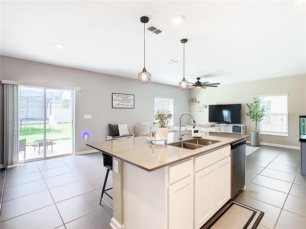 A kitchen island with a sink sits in the foreground of an open-concept living area — 1042 JOHN JACOB ROAD, DAVENPORT, FL