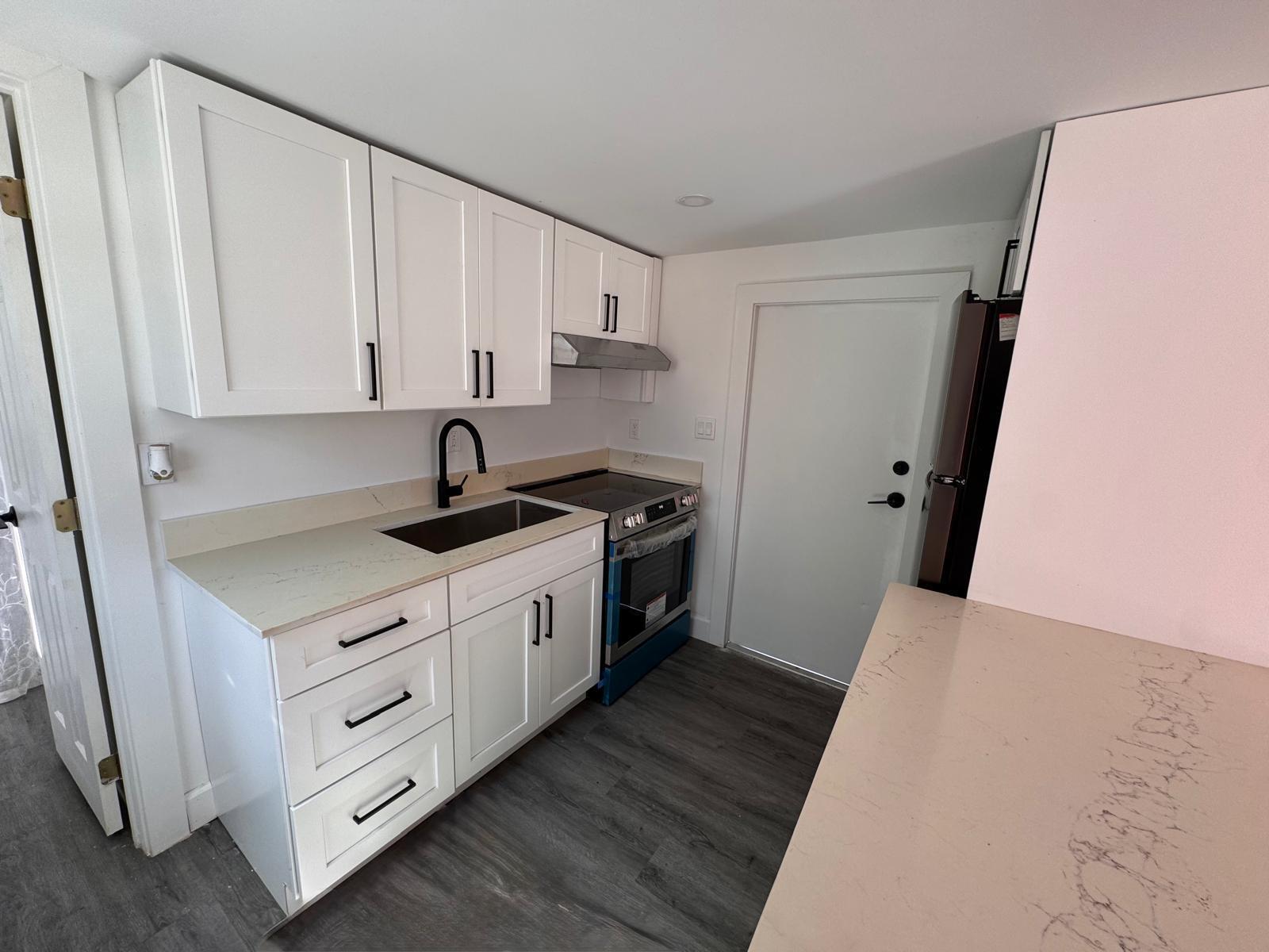 A small kitchen features white cabinets, quartz countertops, a black faucet, and stainless steel appliances — 357 Hunting Club Avenue, Clewiston FL 33440, CLEWISTON, FL