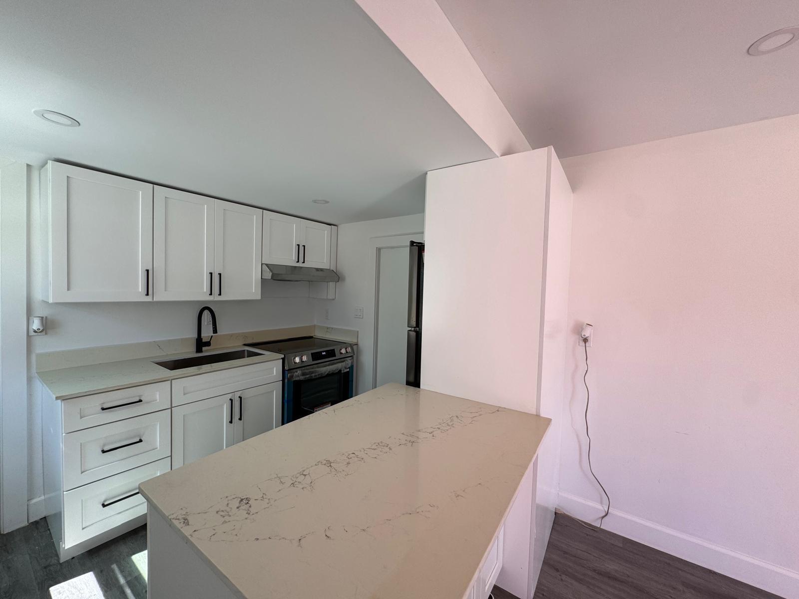 A kitchen features white cabinetry, quartz countertops, a stainless steel stove, and a central island — 357 Hunting Club Avenue, Clewiston FL 33440, CLEWISTON, FL
