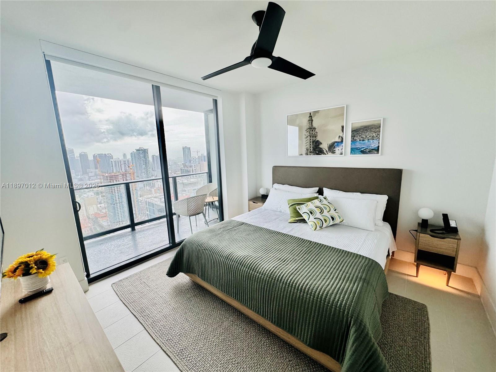 A bedroom features a bed with a green quilt, a ceiling fan, and floor-to-ceiling windows — 159 NE 6th St # 4314, Miami FL 33132, MIAMI, FL