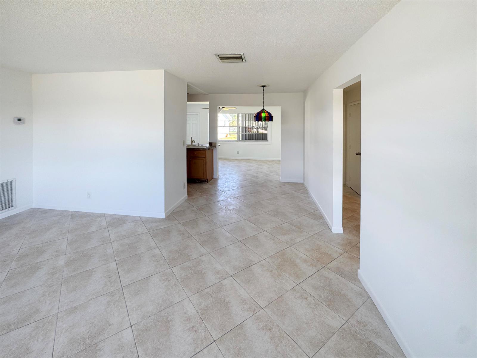 An interior view shows a living area with tile floors leading to a kitchen — 514 SW 20th Street, Boynton Beach FL 33426, BOYNTON BEACH, FL