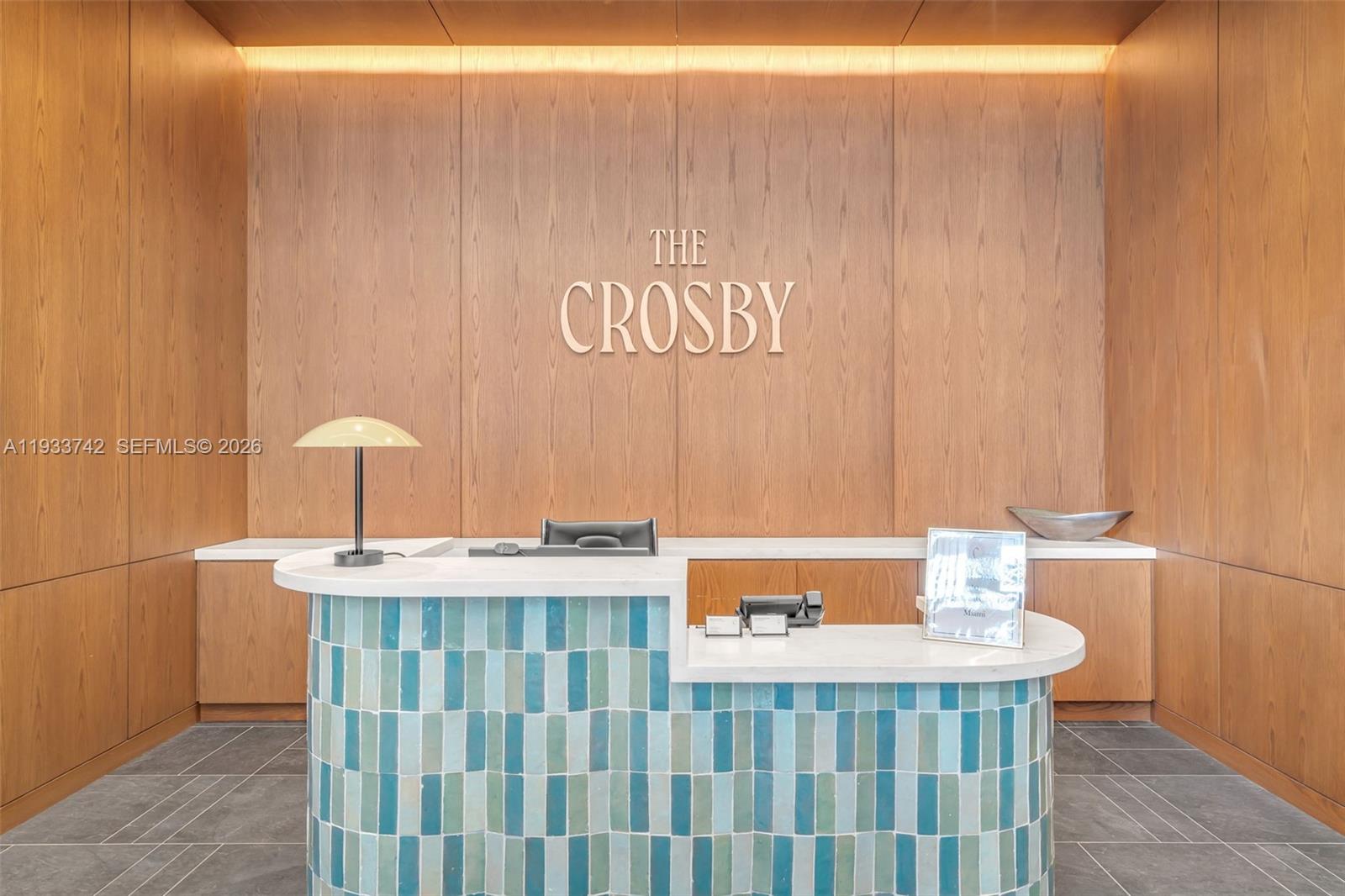 A reception desk with blue tiled front stands in front of a wood-paneled wall — 601 N Miami Ave # 1607, Miami FL 33132, MIAMI, FL