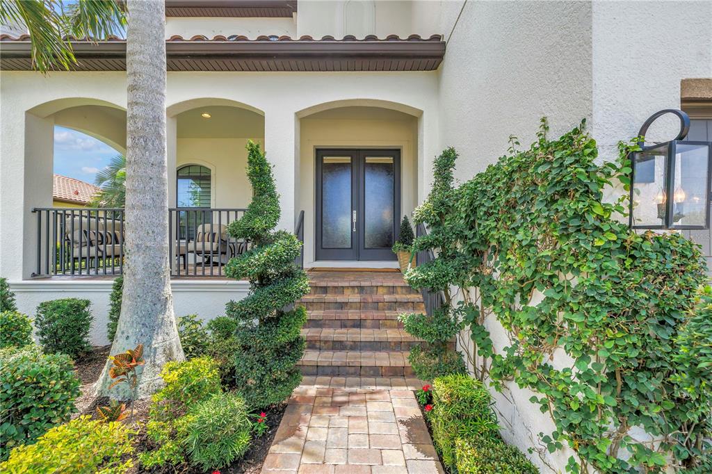 A paved walkway leads to the front entrance of a house with a covered porch — 6237 SIGNATURE POINTE LANE, BRADENTON, FL