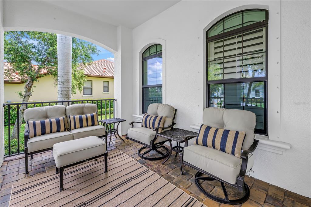 A covered patio features outdoor furniture on a paver floor with views of neighboring homes — 6237 SIGNATURE POINTE LANE, BRADENTON, FL
