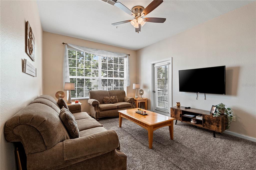 A living room features brown sofas, a wooden coffee table, and a wall-mounted television — 8103 COCONUT PALM WAY UNIT 205, KISSIMMEE, FL