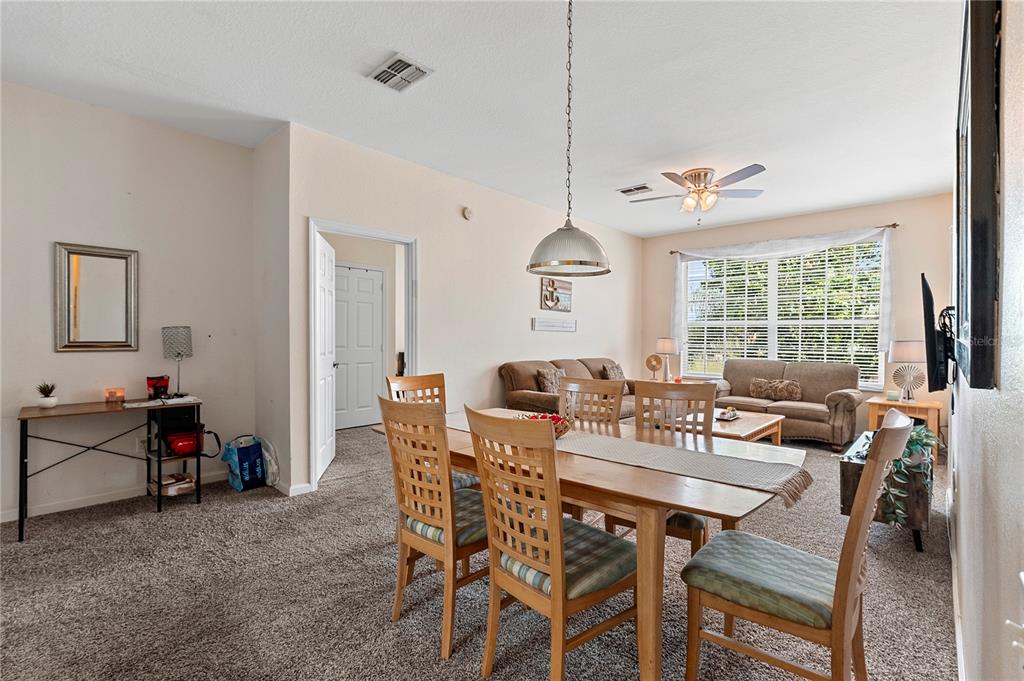 A dining area with a wooden table and chairs sits in front of a living room — 8103 COCONUT PALM WAY UNIT 205, KISSIMMEE, FL