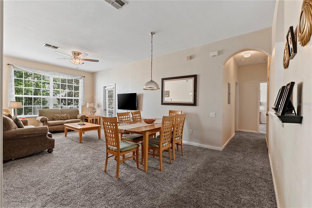 A carpeted living and dining area features a ceiling fan, a dining table, and an archway — 8103 COCONUT PALM WAY UNIT 205, KISSIMMEE, FL