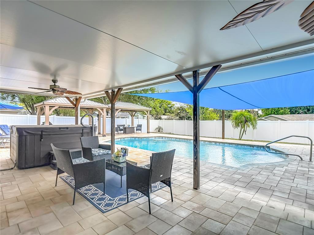 A covered patio features a hot tub, outdoor seating, and a pool with a shade sail — 3008 RIPPLEWOOD DRIVE, SEFFNER, FL