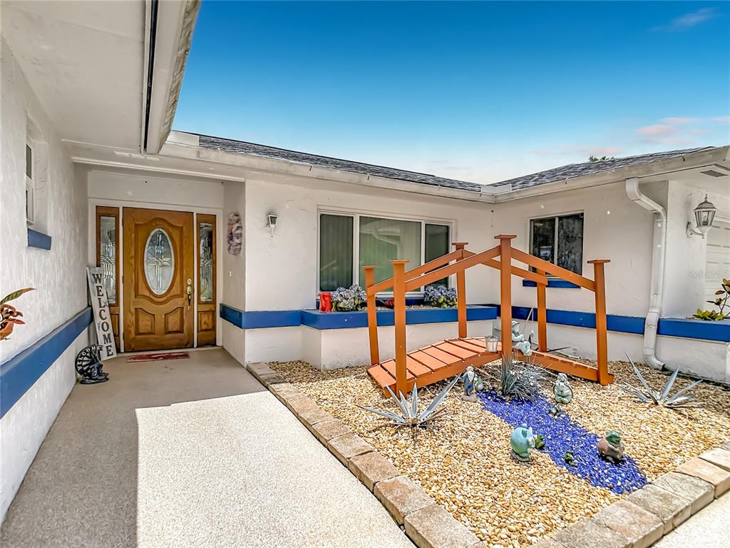 The exterior of a house features a wooden footbridge over a decorative rock garden — 3008 RIPPLEWOOD DRIVE, SEFFNER, FL