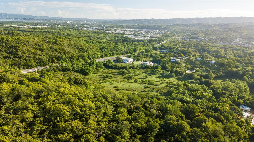 An aerial view shows a lush, hilly landscape with scattered houses and a winding road — 100 PUERTO RICO, CABO ROJO, PR
