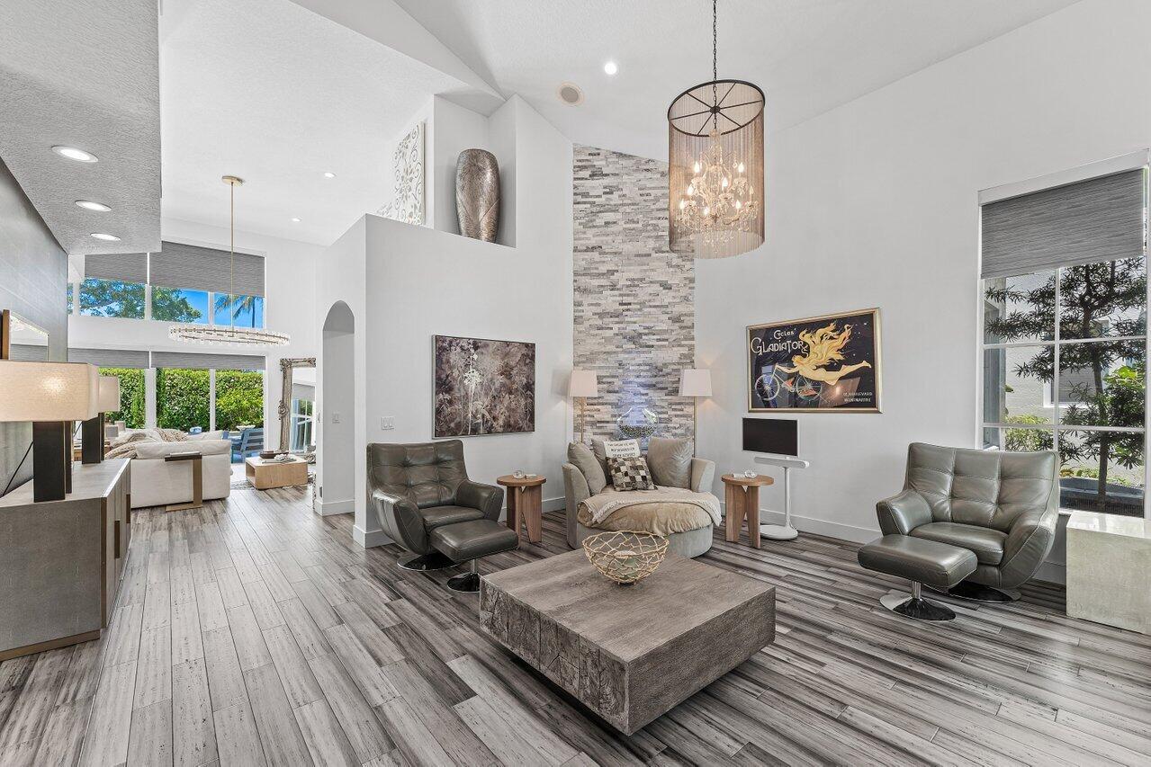 A living room features a stone accent wall, gray leather chairs, and wood-look flooring — 3395 NW 53rd Circle, Boca Raton FL 33496, BOCA RATON, FL