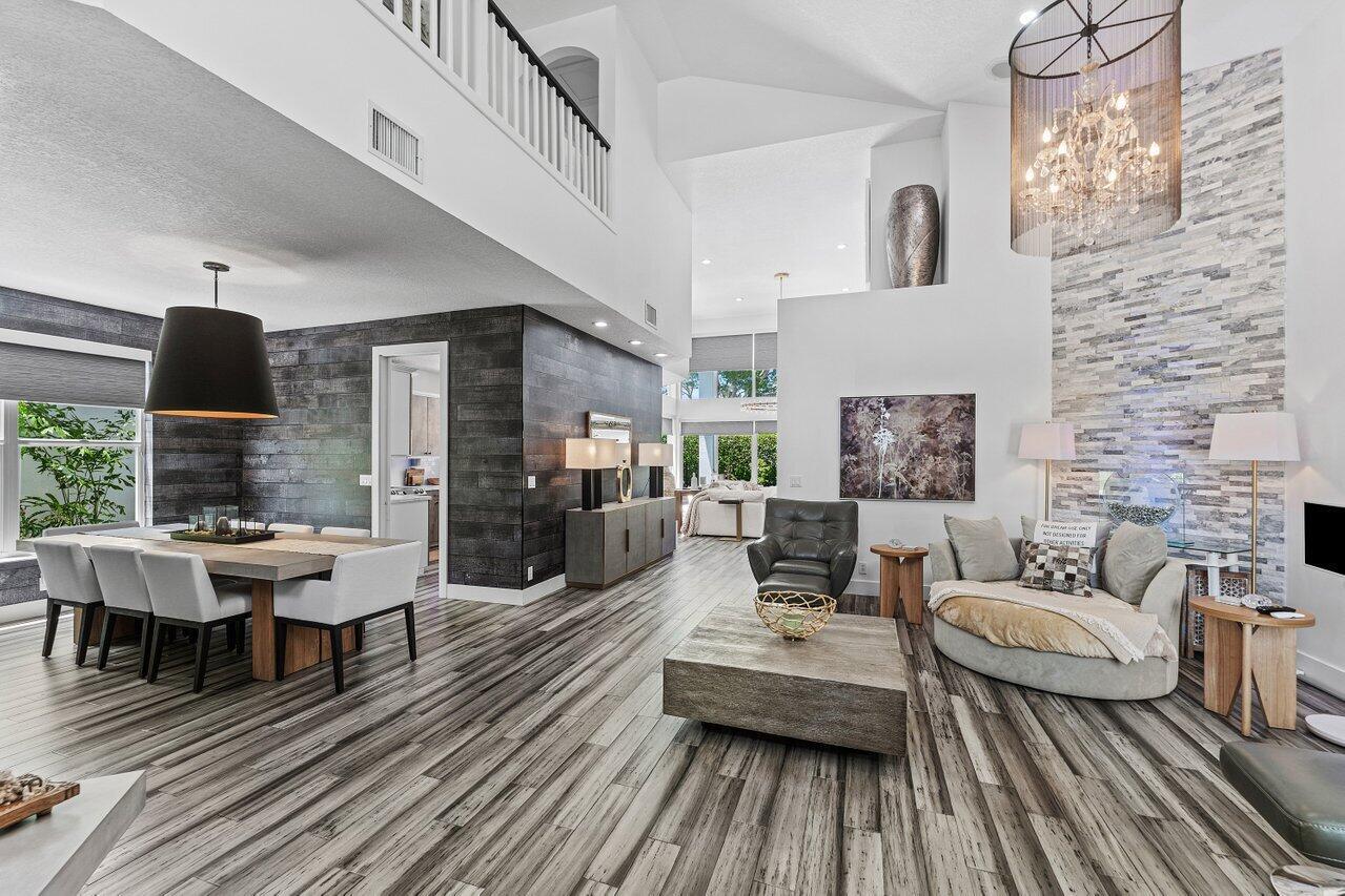 A spacious open-concept living and dining area features wood-look flooring and a stone fireplace wall — 3395 NW 53rd Circle, Boca Raton FL 33496, BOCA RATON, FL