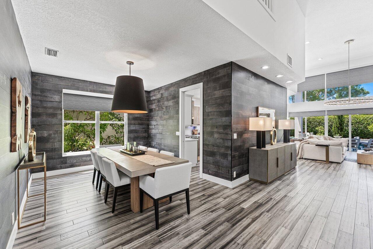 A dining room features dark wood-plank walls, a rectangular table, and light wood-look flooring — 3395 NW 53rd Circle, Boca Raton FL 33496, BOCA RATON, FL