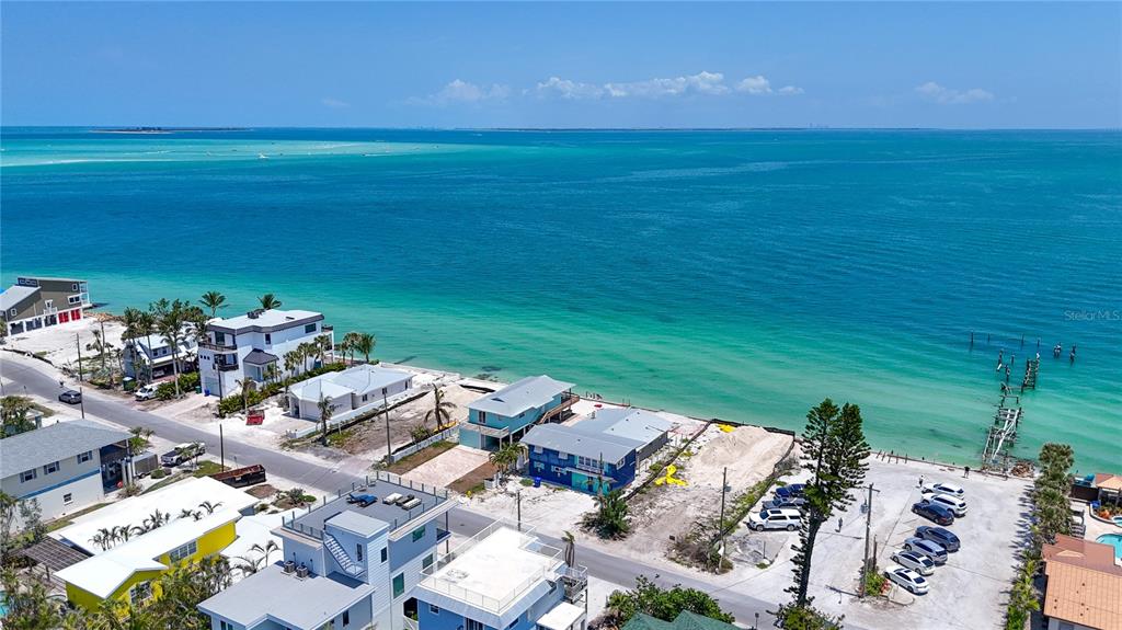 An aerial view shows several beach houses along a coastline with turquoise water and docks — 873 N SHORE DRIVE, ANNA MARIA, FL