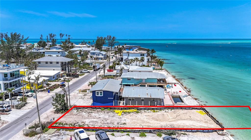 An aerial view shows a vacant, fenced-in waterfront lot next to several houses — 873 N SHORE DRIVE, ANNA MARIA, FL