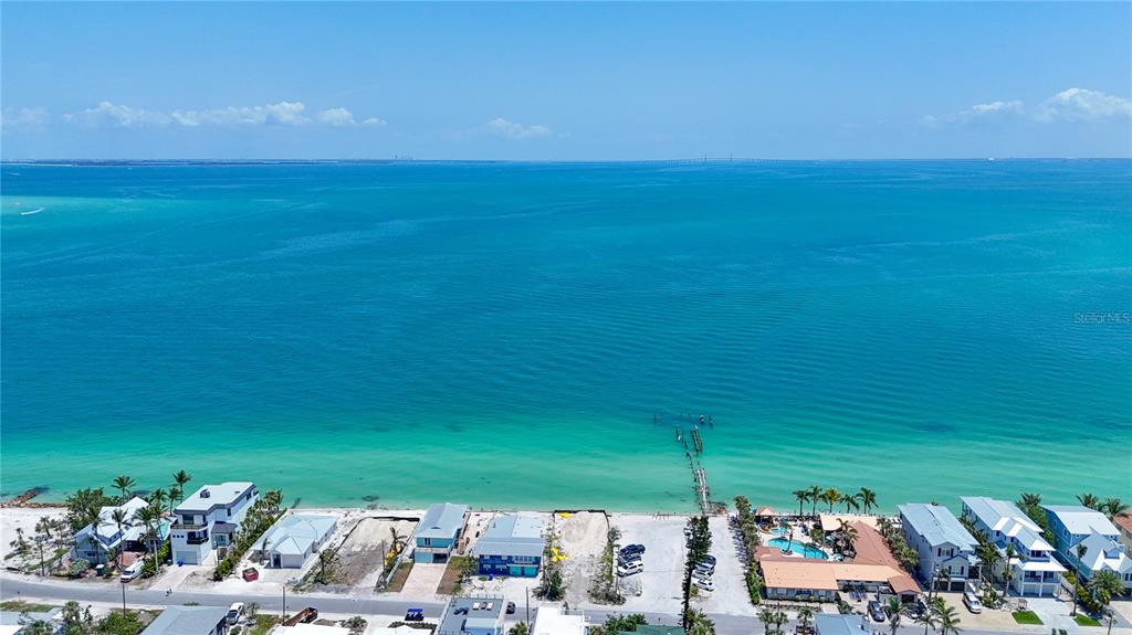 An aerial view shows a row of beachfront houses along a turquoise ocean — 873 N SHORE DRIVE, ANNA MARIA, FL