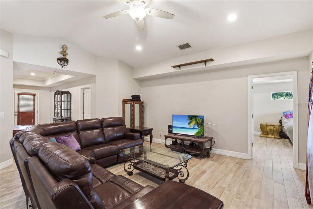 A living room features a brown leather sectional, a glass coffee table, and tile flooring — 126 GREEN PINE PARK, ROTONDA WEST, FL