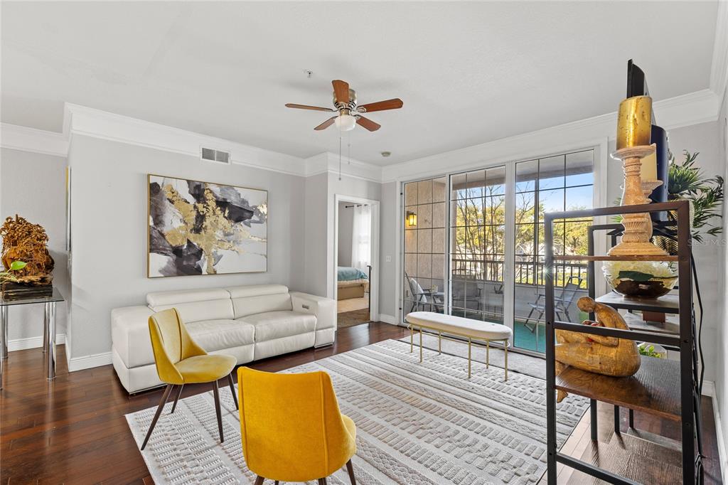 A living room features a white sofa, two yellow chairs, and a sliding glass door — 3480 SOHO STREET UNIT 201, ORLANDO, FL