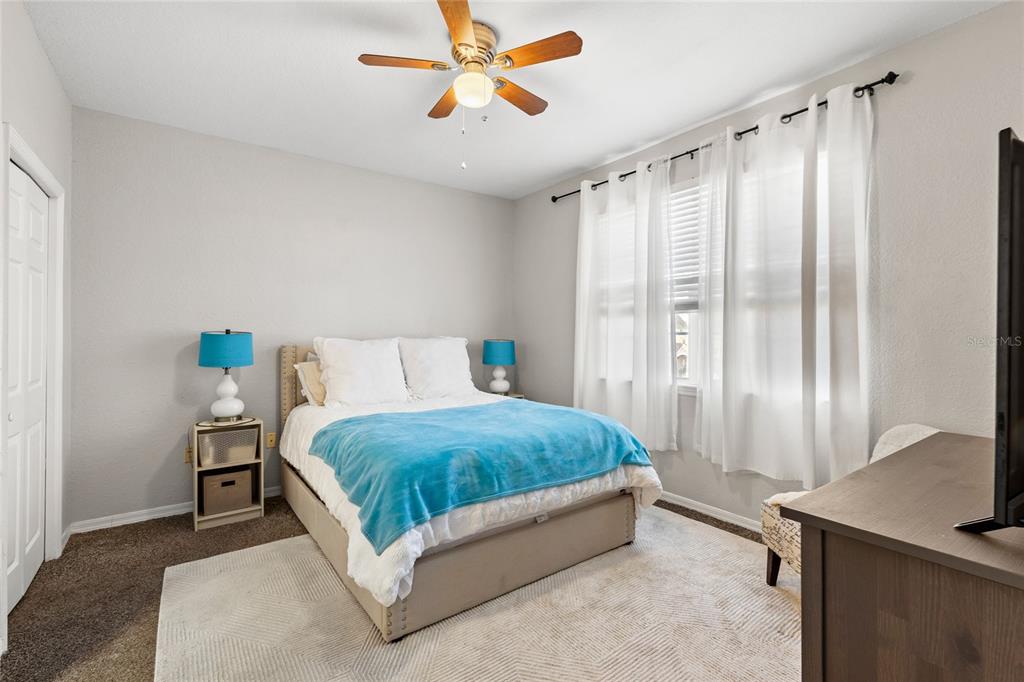 A bedroom features a bed with a blue throw, two nightstands, and a ceiling fan — 3480 SOHO STREET UNIT 201, ORLANDO, FL