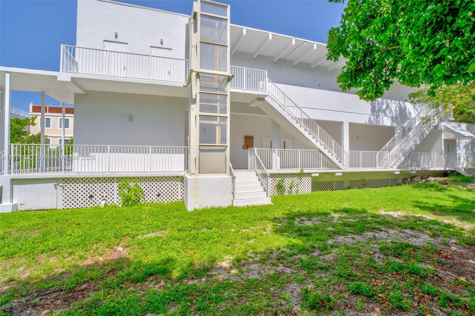 A multi-story white building features an exterior elevator shaft, metal railings, and outdoor staircases — 14 125th Street Gulf, Marathon FL 33050, MARATHON, FL
