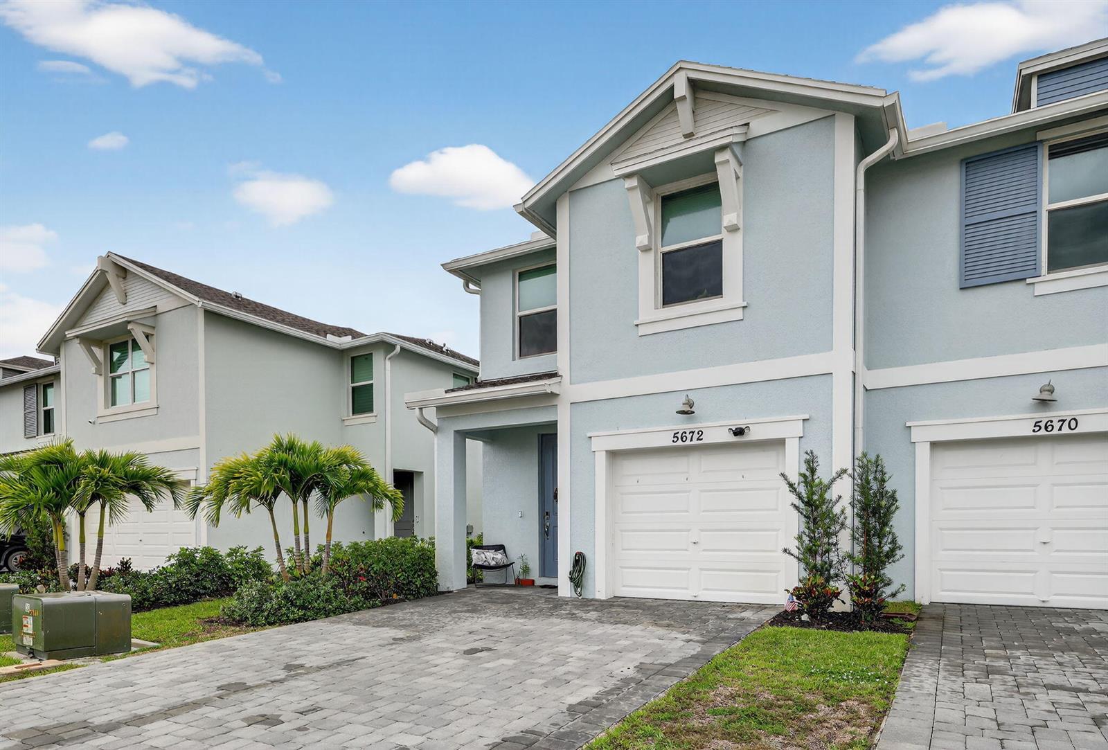 The exterior of two light blue townhouses features white garage doors and paved driveways — 5672 SE Edgewater Circle, Stuart FL 34997, STUART, FL