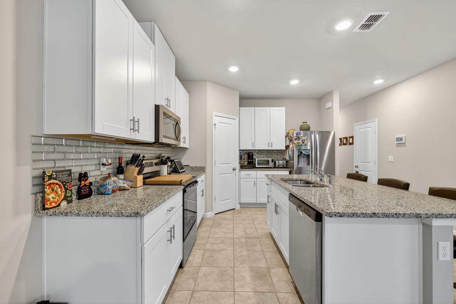 A kitchen features white cabinetry, granite countertops, stainless steel appliances, and a central island — 5672 SE Edgewater Circle, Stuart FL 34997, STUART, FL