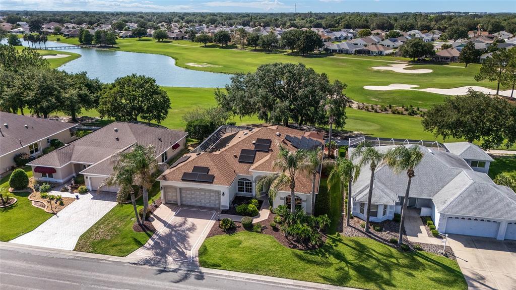 An aerial view shows a suburban house with solar panels on the roof near a golf course — 1322 AUGUSTINE DRIVE, THE VILLAGES, FL