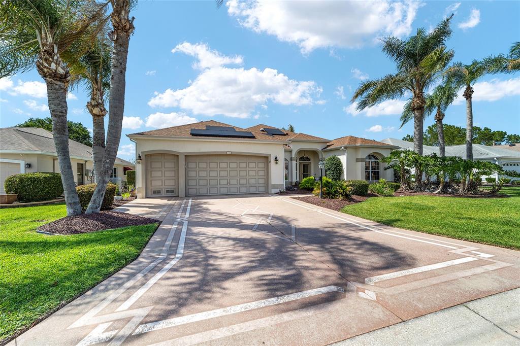 A single-story house with a three-car garage, a paved driveway, and several palm trees — 1322 AUGUSTINE DRIVE, THE VILLAGES, FL