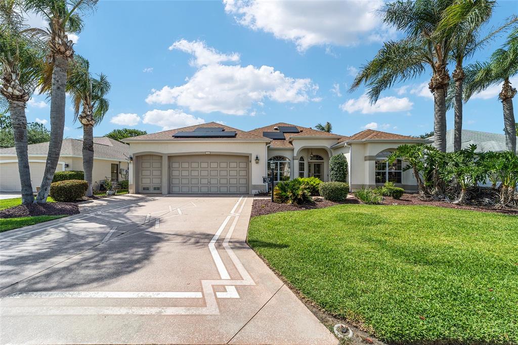 A single-story house with a beige exterior, a three-car garage, and palm trees — 1322 AUGUSTINE DRIVE, THE VILLAGES, FL