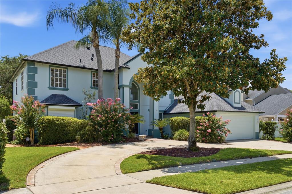 A two-story house with a curved driveway, a large tree, and pink flowering bushes — 1307 HAMPSTEAD TERRACE, OVIEDO, FL