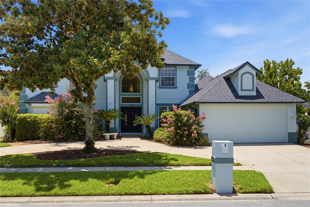 A two-story house with a blue exterior, a large tree, and an attached two-car garage — 1307 HAMPSTEAD TERRACE, OVIEDO, FL