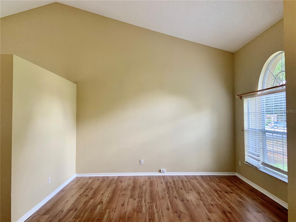 An empty room with vaulted ceilings, wood-look flooring, and a large arched window — 3878 KINGSTON OAKS COVE, OVIEDO, FL