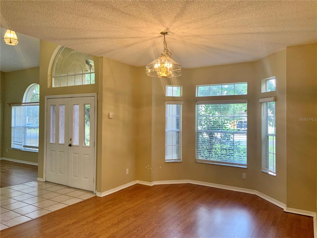 A dining area with hardwood floors, a chandelier, and large windows near an entryway — 3878 KINGSTON OAKS COVE, OVIEDO, FL