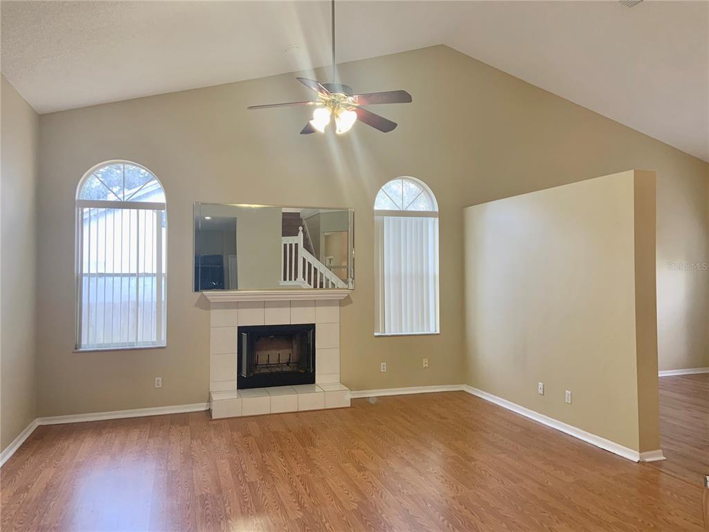 A living room with wood flooring, a fireplace, a ceiling fan, and arched windows — 3878 KINGSTON OAKS COVE, OVIEDO, FL