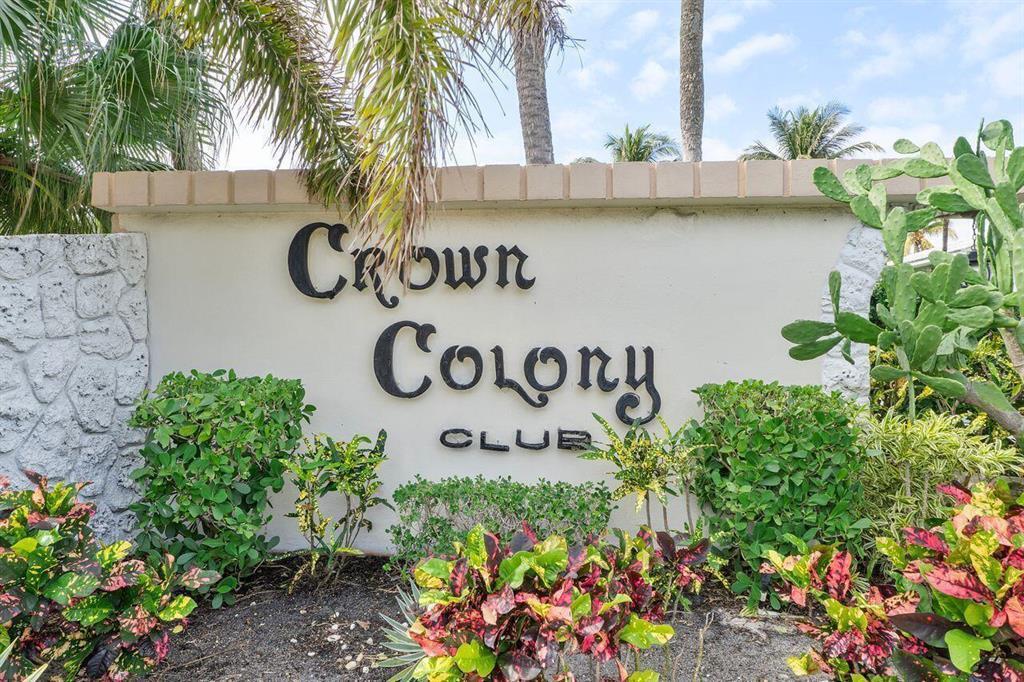 A sign for Crown Colony Club stands in front of lush tropical landscaping and palm trees — 5540 N Ocean Boulevard # 110, Ocean Ridge FL 33435, OCEAN RIDGE, FL