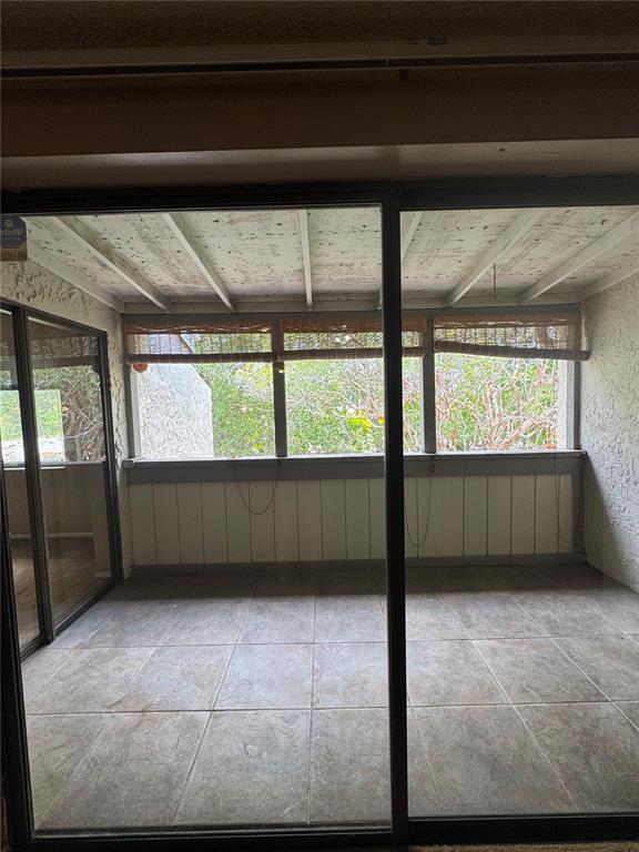 A sunroom with tiled flooring, a slatted wood ceiling, and large windows overlooking trees — 5359 VINELAND ROAD UNIT 2E, ORLANDO, FL