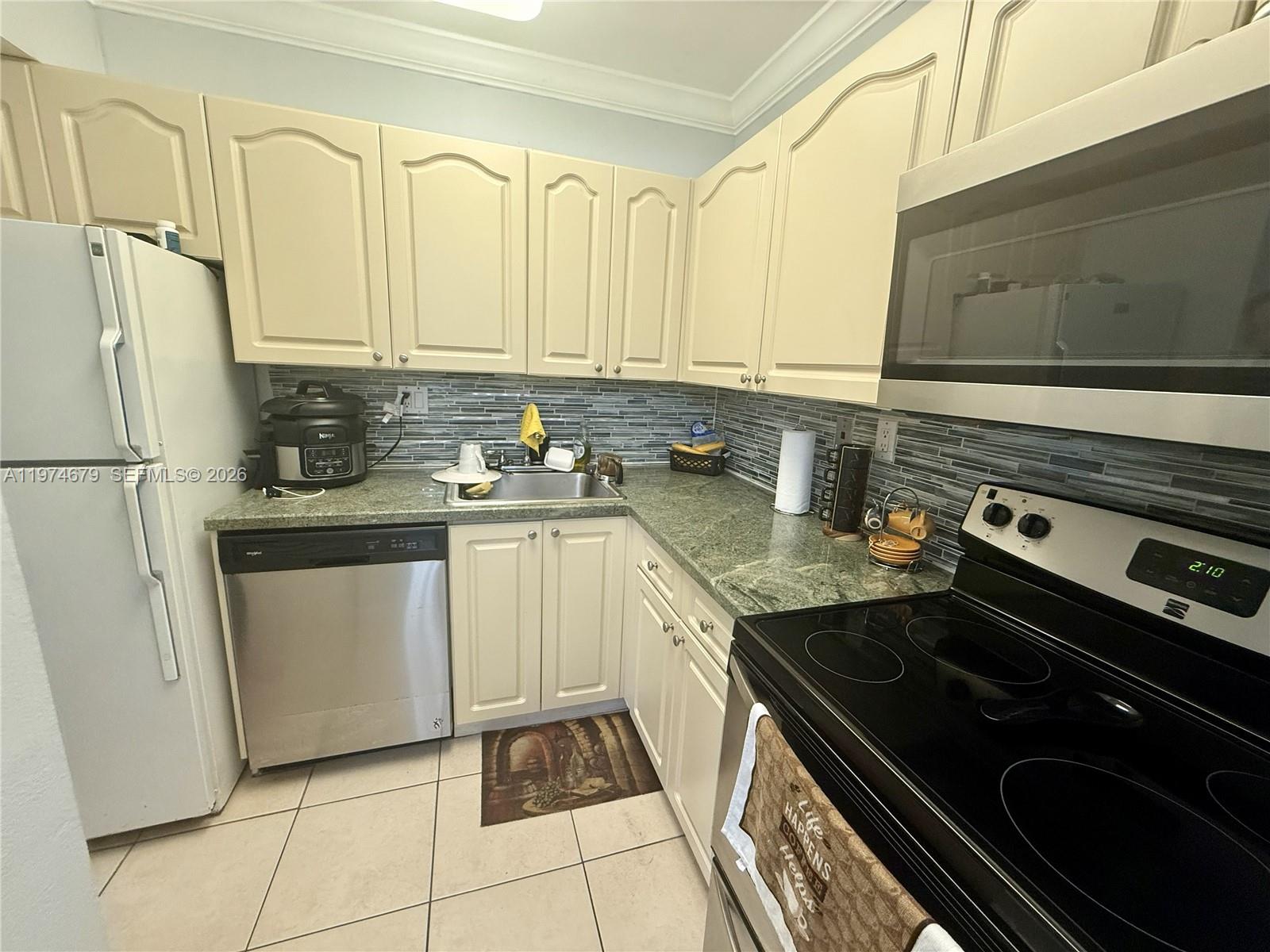 A kitchen features cream-colored cabinets, stainless steel appliances, and a green granite countertop — 10413 N Kendall Dr # B208, Miami FL 33176, MIAMI, FL