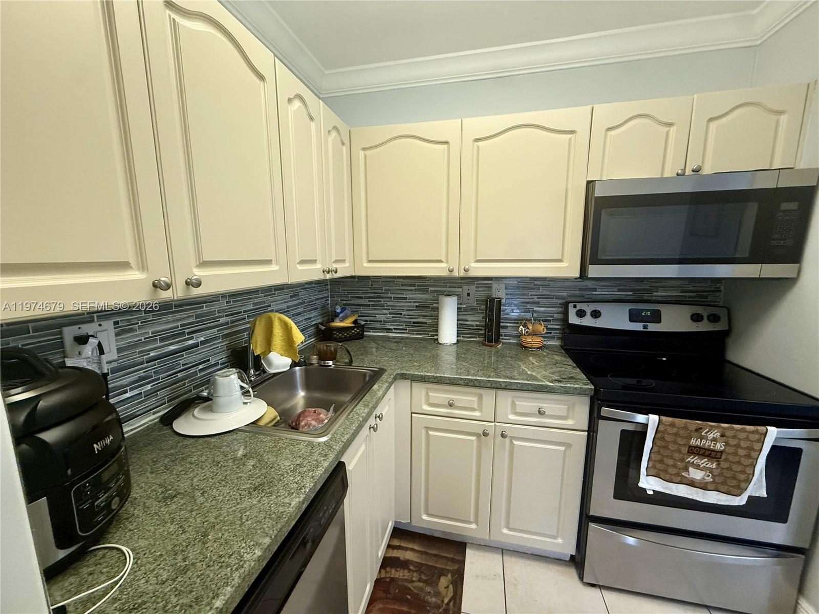 A kitchen features cream-colored cabinets, green granite countertops, a stainless steel stove, and backsplash — 10413 N Kendall Dr # B208, Miami FL 33176, MIAMI, FL