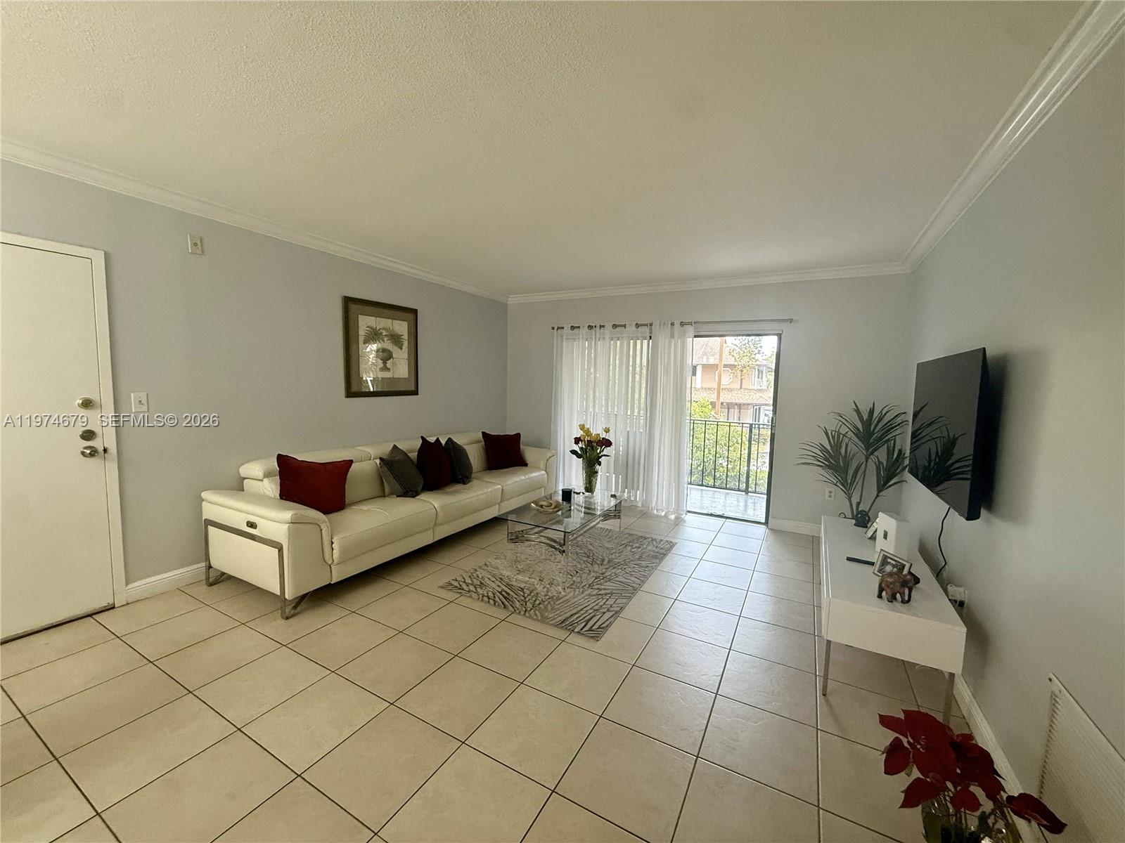 A living room features a white leather sofa, tile flooring, and a sliding glass door — 10413 N Kendall Dr # B208, Miami FL 33176, MIAMI, FL