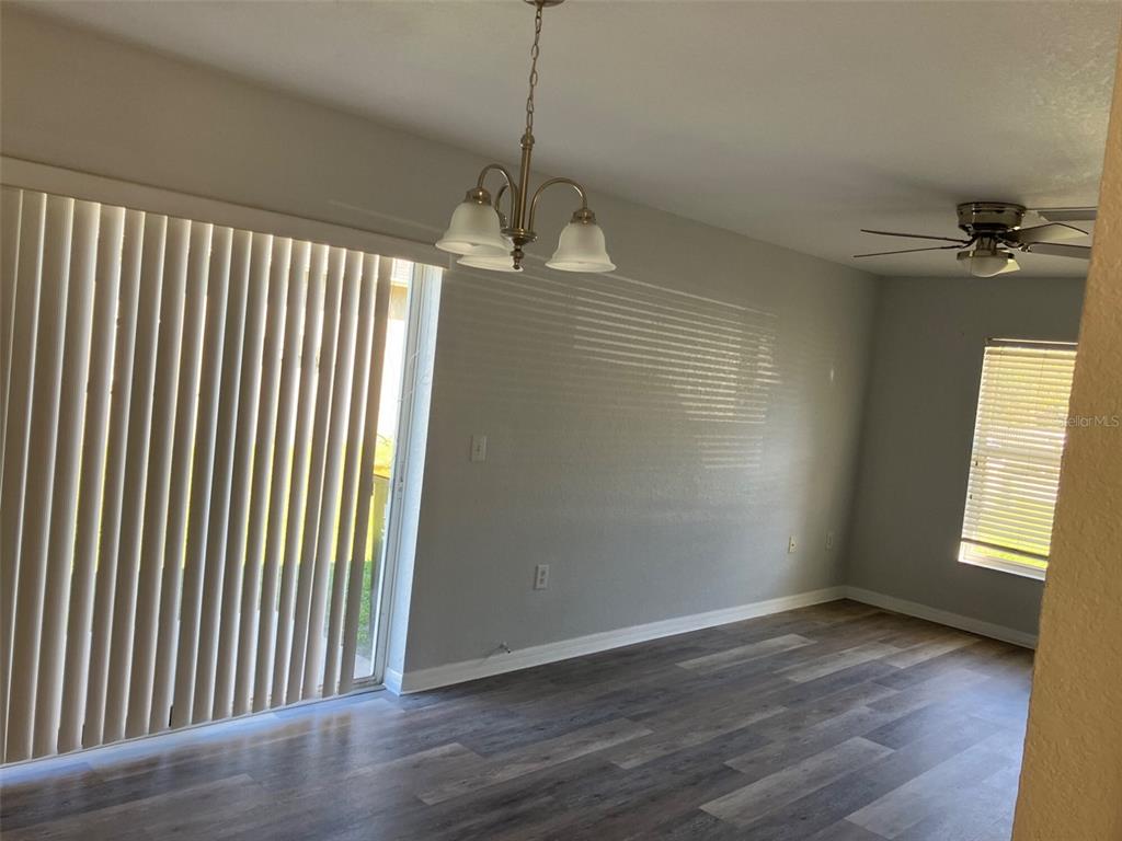 A dining area features wood-look flooring, a chandelier, vertical blinds, and a ceiling fan — 5527 GAUR LANE, LAKELAND, FL
